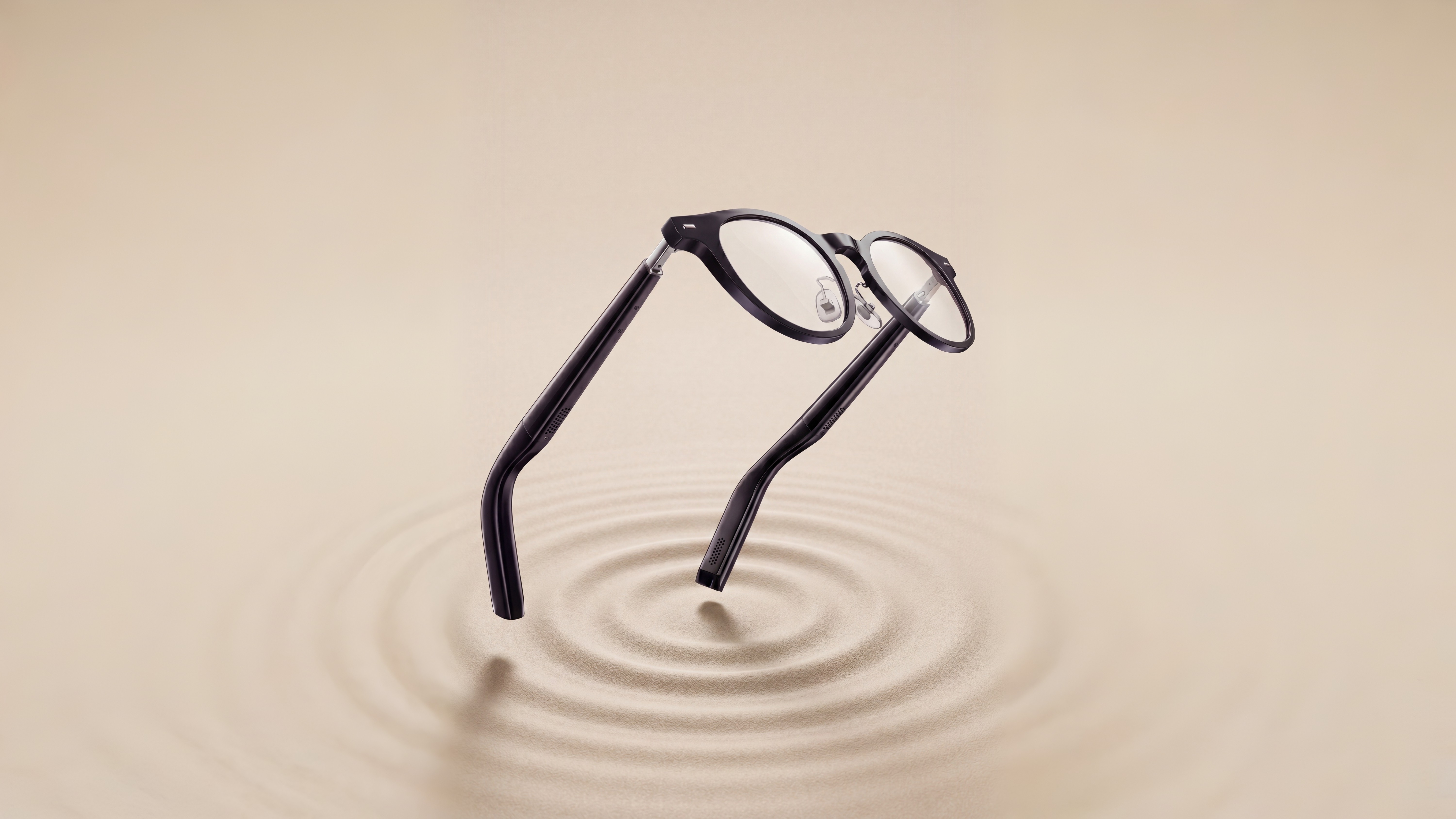 Black optical smart eyewear floating above a circular sand ripple