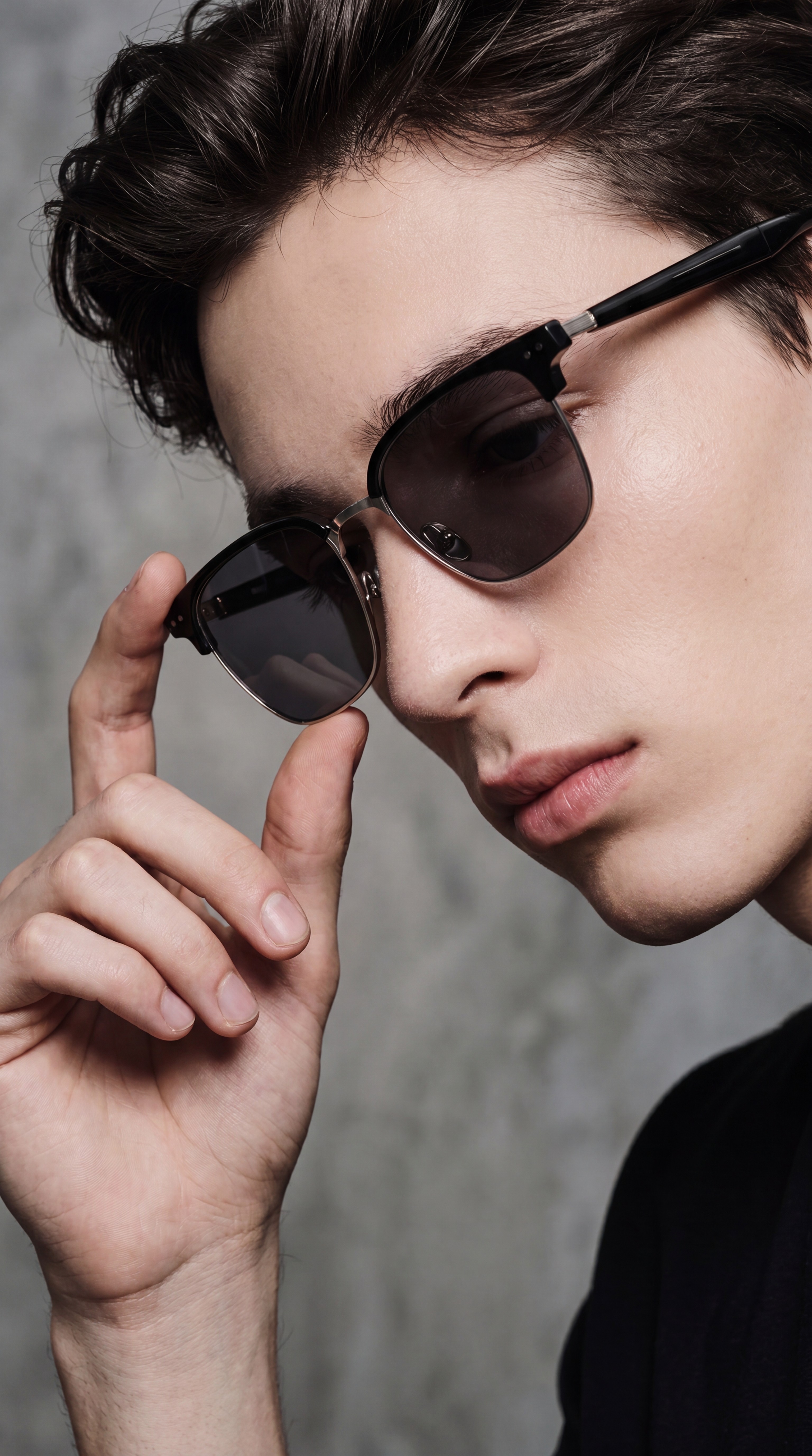 Close-up portrait of a model adjusting refined sunglasses